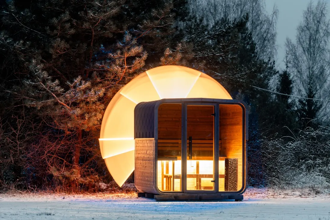 A modern cube-shaped outdoor sauna at dusk