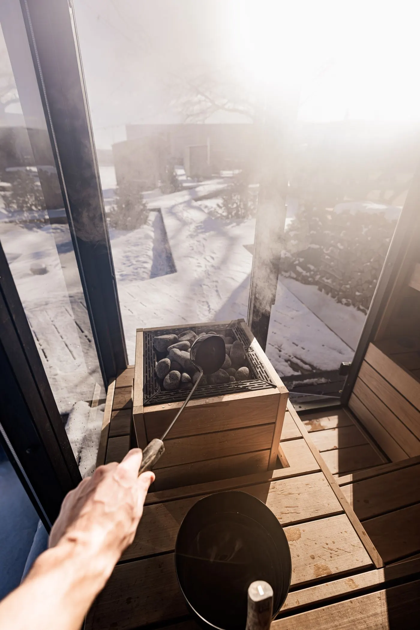 Sauna interior with a window to the snow and heater stones